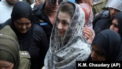 Police officers escort Maryam Nawaz when she appears in an accountability court in Lahore on August 9.