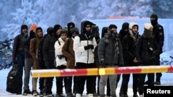Migranți așteptând în frigul iernii finlandeze la punctul de trecere a frontierei cu Rusia Salla, din nordul țării, în noiembrie 2023.