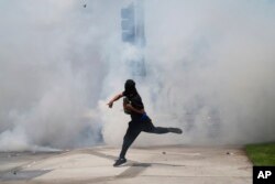 Протестиращ хвърля камък на фона на сълзотворен газ от органите на реда по време на демонстрация в събота, 7 юни 2025 г., в Парамаунт, Калифорния.