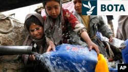 Një vajzë duke u furnizuar me ujë në një hapësirë publike në Kabul, derisa të tjerët tentojnë ta kapin radhën. 