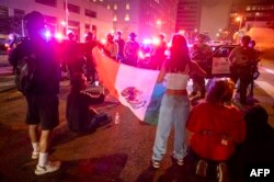 Протестиращи с мексиканско знаме, изправени пред служители на полицията. Лос Анджелис, 8 юни.