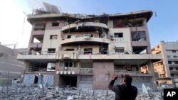 Мъж прави снимки с мобилния си телефон на разрушения си апартамент в Дахия, в южното предградие на Бейрут.