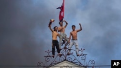 Demonstranti slave na vrhu vladine zgrade u kojoj su smještene brojne ministarske kancelarije koji su zapalili tokom protesta 9. septembra