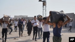 Palestinezët pasi kanë marrë ndihma humanitare të shpërndara nga GHF-ja në Rafah më 27 maj 2025. 