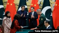 FILE: Pakistani Prime Minister Imran Khan (center L) and Chinese Premier Li Keqiang (centre R) applaud during a signing ceremony at the Great Hall of the People in Beijing on October 8.