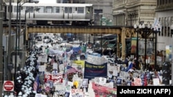 Сотни чикагских полицейских в спецодежде окружают группу из нескольких тысяч протестующих, идущих по Мичиган-авеню, под рельсами «EL», 5 апреля 2003 года в Чикаго, штат Иллинойс.