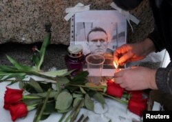 Ndezja e qirinjve pranë një portreti të Navalnyt që u vendos afër monumentit për viktimat e shtypjes politike në Shën Petersburg.
