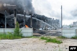 O fotografie publicată de Serviciul de urgență ucrainean pe 6 iunie 2025 arată un pompier stingând un incendiu într-o instalație industrială în urma unui atac rus în regiunea Ternopil.