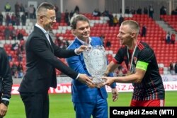 Szijjártó Péter külügyminiszter a másodosztályú bajnoki serleget nyújtja át Dzsudzsák Balázs debreceni focistának 2021. május 6-án. Középen Bánki Erik fideszes képviselő.