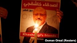 FILE: A demonstrator holds a poster with a picture of Saudi journalist Jamal Khashoggi outside the Saudi Arabia consulate in Istanbul in October.