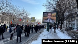 Un manifestant aruncă cu un bulgăre de zăpadă într-un panou pre-electoral al lui Nicușor Dan, primarul general al Capitalei, care și-a anunțat intenția de a candida la alegerile din mai, 22 februarie 2025.