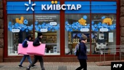 Луѓет поминуваат покрај продавницата на „Киевстар“, украинска телекомуникациска компанија во Киев, на 12 декември 2023 година.