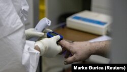 Zdravstveni radnik u Kliničko-bolničkom centru Zemun meri zasićenost kiseonika u krvi pacijenta (ilustrativna fotografija)