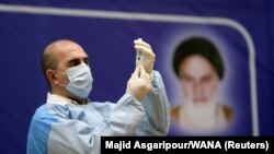 Një zyrtar iranian i shëndetësisë duke mbushur një shiringë me vaksinën ruse kundër koronavirusit, Sputnik V, në Teheran. Shkurt, 2021.