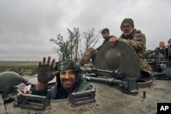 Un soldat ucrainean zâmbește dintr-un vehicul militar pe un drum pe teritoriul eliberat în regiunea Harkov, Ucraina, 12 septembrie 2022.