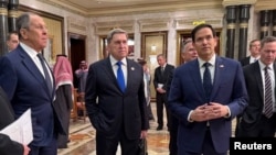 Снимката е публикувана от руското външно министерство в социалната мрежа „X“. На нея се виждат на предел план руският външен министър Сергей Лавров (ляво), съветникът на руския президент Юрий Ушаков и държавният секретар на САЩ Марко Рубио. Рияд, 18 февруари 2025 г.