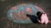 Un copil desenează globul pământesc cu creta pe asfalt la Kiev de Ziua Pământului în 22 aprilie 2006, la un eveniment menit să atragă atenția asupra deteriorării mediului. 