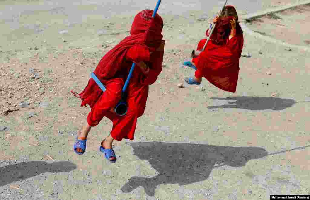 Devojčice pokrivenog lica se ljuljaju na ljuljaškama tokom prvog dana Kurban-bajrama. (Kabul, 11. avgust 2019)