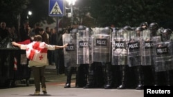 Протестираща с грузинското знаме се разхожда пред полицейски кордон в столицата Тбилиси, 4 октомври 2025 г.