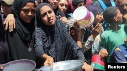 Disa palestinezë duke pritur të marrin ushqime nga një kuzhinë bamirëse në pjesën qendrore të Gazës. Korrik, 2025.