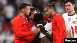 Csapattársai vigasztalják Bukayo Sakát a mérkőzés után Londonban 2021. július 11-én