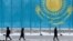 Люди на улице в Астане на фоне флага Казахстана