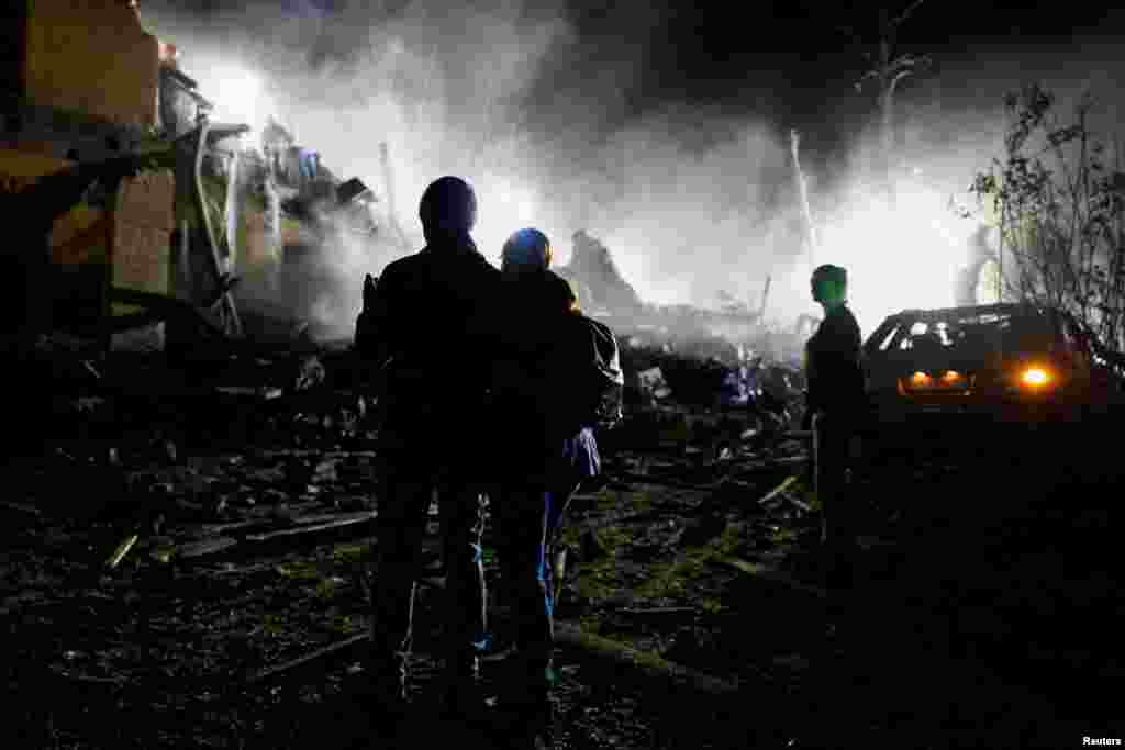 Жители дома, поврежденного российским ударом, наблюдают за расчисткой завалов в надежде на спасение своих родных, Киев