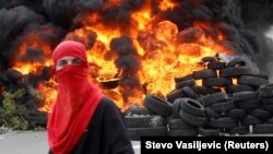 Një protestues para një barrikade të djegur gjatë protestave kundër ceremonisë së shugurimit të Mitropolitit Joanikije në Cetinje, Mali i Zi, 5 shtator 2021.