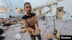 Un palestinian ține în mână paste la locul unui atac israelian asupra unui depozit de ajutoare, în tabăra de refugiați Al-Nuseirat din centrul Fâșiei Gaza. Reuters, 14 martie 2024.