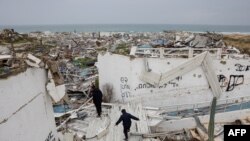 Mladi hodaju po ruševinama grada Gaze tokom trenutnog prekida vatre.