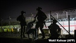 Британски и канадски војници му помагаат на Авганистанец во близина на аеродромот во Кабул, контролиран од странската војска, 22 август 2021 година