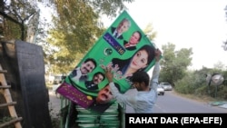 Supporters of opposition political party Pakistan Muslim League Nawaz (PMLN) install posters at the party's senior leaders residence in Lahore as major political parties gear up for an anti-government rally on October 15 