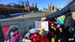 Un bărbat pune un bilet pe care scrie „Nu războiului!” în locul unde liderul opoziției Boris Nemțov a fost împușcat mortal, în apropierea Kremlinului. Imagine din 27 februarie 2022, la a șaptea aniversare a asasinării opozantului rus.