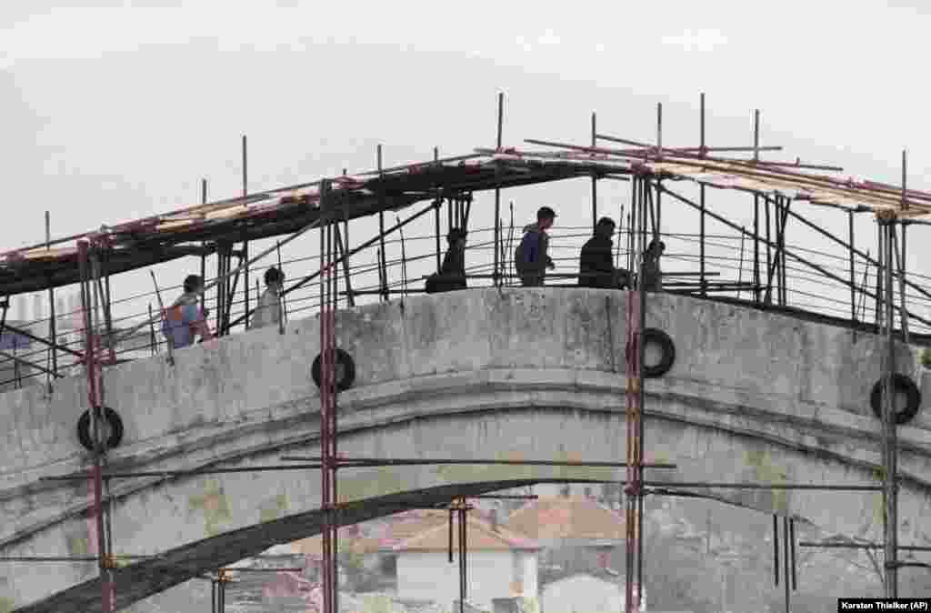 Stanovnici Mostara prelaze preko oštećenog i jedva zaštićenog Starog mosta koji će za samo nekoliko mjeseci biti srušen, 12. april 1993. godine
