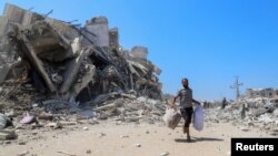 Palestinac trči sa stvarima pored ruševina nakon što je zgrada pogođena izraelskim vazdušnim napadom, u gradu Gazi, 5. septembra 2025.