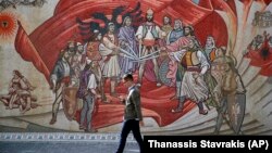 Një person kalon pranë një murali me motive etnike shqiptare. Shkup, 2018.
