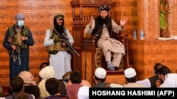 Luftëtarë talibanë të armatosur qëndrojnë pranë një imami gjatë Lutjeve të së Premtes në xhaminë Abdul Rahman në Kabul më 20 gusht 2021. 