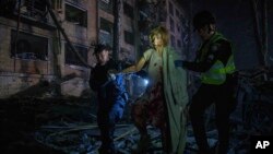 Polițiști ucraineni ajută o femeie rănită să iasă din casa sa de la Kiev, grav avariată de o rachetă rusească, pe 24 aprilie 2025