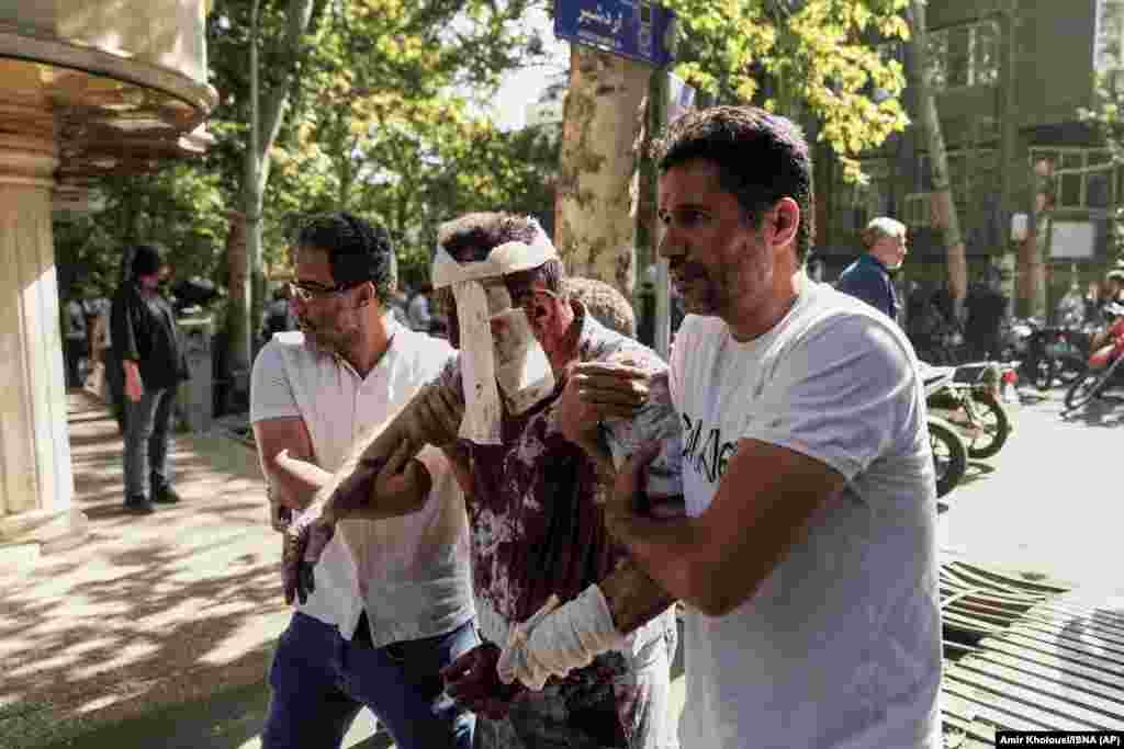 Një burrë i plagosur duke u ndihmuar që të largohet nga vendi i një shpërthimi në Teheran, më 15 qershor.