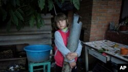 A hétéves Veronika Tkacsenko egy Grad rakéta darabját tartja a kezében 2022. szeptember 15-én. A rakéta röviddel korábban találta el a házukat Izjumban