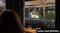 Dva policajca šetaju blizu kafića u Vučitrnu.