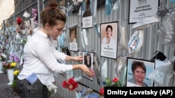 Volonteri brišu prašinu sa portreta sanktpeterburških medicinskih radnika koji su umrli od korona virusa na nezvaničnom spomen obeležju ispred lokalnog zdravstvenog odeljenja. Najmlađa radnica kojoj je odata čast je 30-godišnja medicinska sestra Marija Tiško.