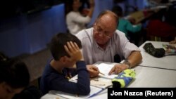 Spanyol önkéntes segít a kisgyereknek a házifeladatánál, Murciában, 2015. november 3-án. 