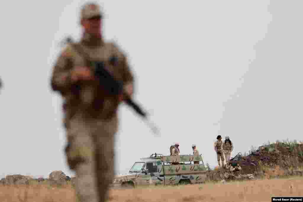 Турски војник, со ирански војници во позадина, чува стража на турско-иранската граница во провинцијата Ван