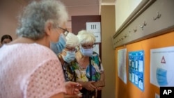 Жени оглеждат инструкциите за гласуване с машина, 11 юли 2021 г.