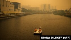 Vízibiciklizik egy pár Jakutszkban, 2021. július 27-én. A szibériai várost a környező erdőtüzek füstje borítja be