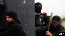 Një luftëtar turk i grupit xhihadist Al-Nusra Front, duke mbajtur flamurin e Al-Kaidës në xhaketën e tij (në mes), mban pozicion me shokë në afërsi të Aleppos, Siri.