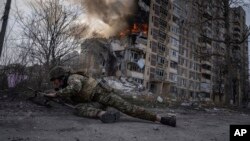 Украински полицай се прикрива пред горяща сграда, пострадала при руски въздушен удар в Авдиивка през март 2023 г