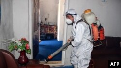 A municipal worker wearing protective gear sprays disinfectant as a preventive measure against the spread of the COVID-19 coronavirus at a local radio station in the northeastern Kunduz Province on June 3.