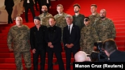 Боно, Эдж и Шон Пенн вместе с украинскими военнослужащими на красной дорожке 78-го Каннского кинофестиваля перед показом документального фильма «Bono: stories of surrender» («Боно: Истории капитуляции»). Канны, Франция, 16 мая 2025 года